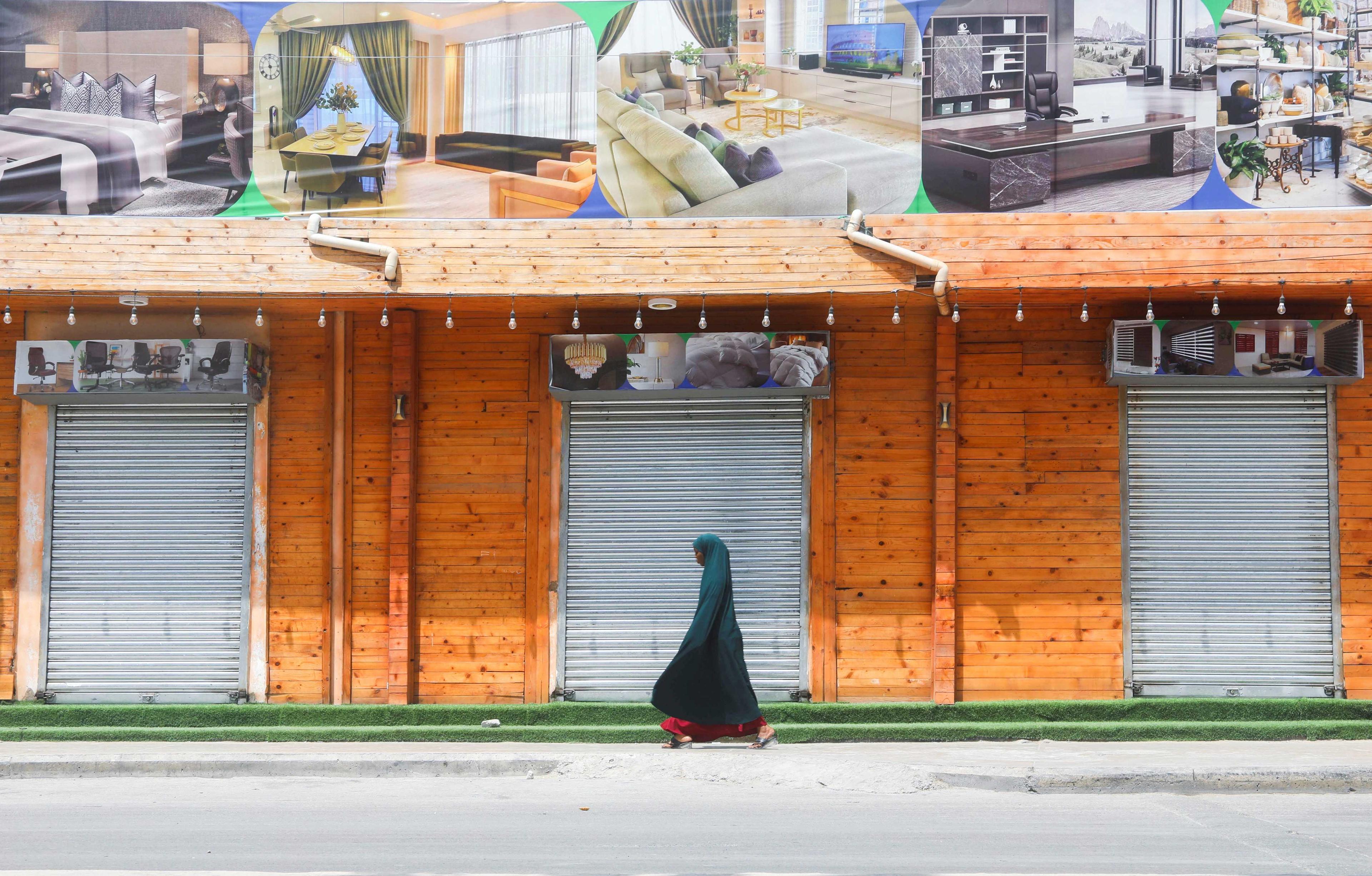A Somali woman walks past a closed furniture shop in Mogadishu, Somalia Dec 5. Photo: Reuters