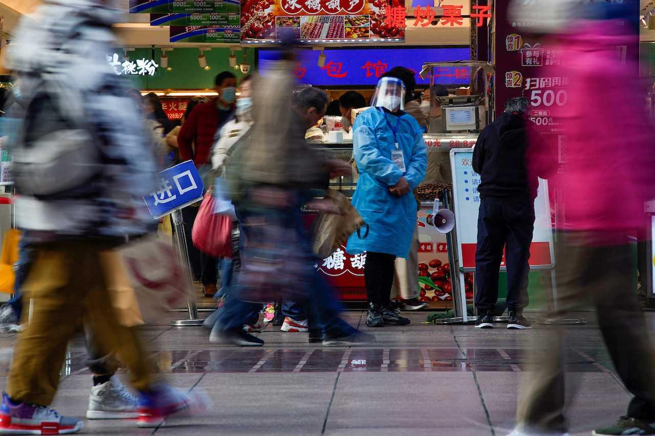 A worker in a protective suit stands at a food shop, as Covid-19 outbreaks continue in Shanghai, China, Dec 12. Photo: Reuters 
