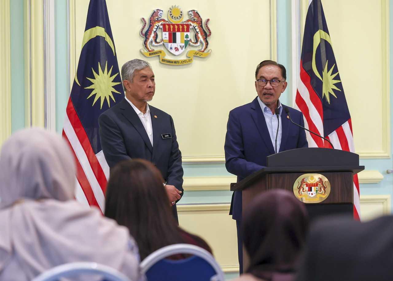 Deputy Prime Minister Ahmad Zahid Hamidi stands beside Prime Minister Anwar Ibrahim at a press conference in Putrajaya on Dec 14. Photo: Bernama
