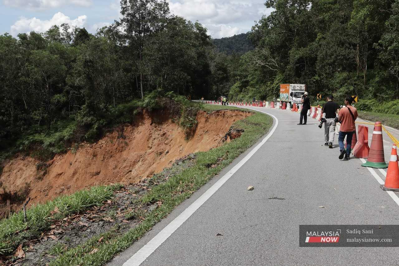 Petugas media berjalan di sekitar kawasan tanah runtuh di Batang Kali hari ini.