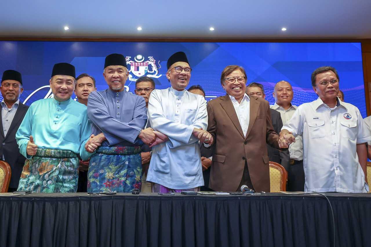 Prime Minister Anwar Ibrahim (centre) links arms with (from left) Gabungan Rakyat Sabah chairman Hajiji Noor, Barisan Nasional chairman Ahmad Zahid Hamidi, Gabungan Parti Sarawak chairman Abang Johari Openg, and Warisan president Shafie Apdal at the signing of a memorandum of understanding in Putrajaya yesterday. Photo: Bernama