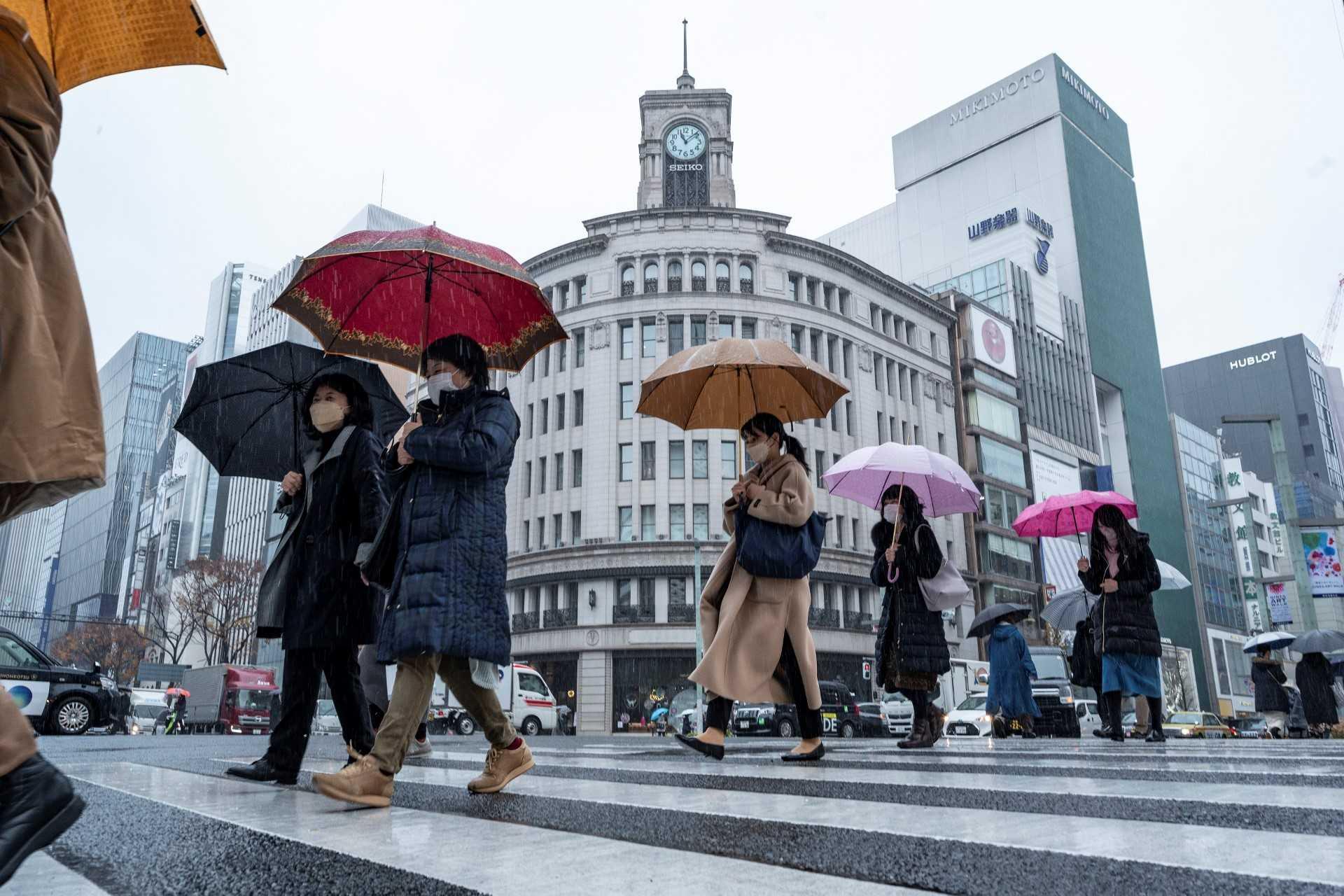 People cross the street on a cold and rainy day in the Ginza area of Tokyo on Dec 22. Photo: AFP 