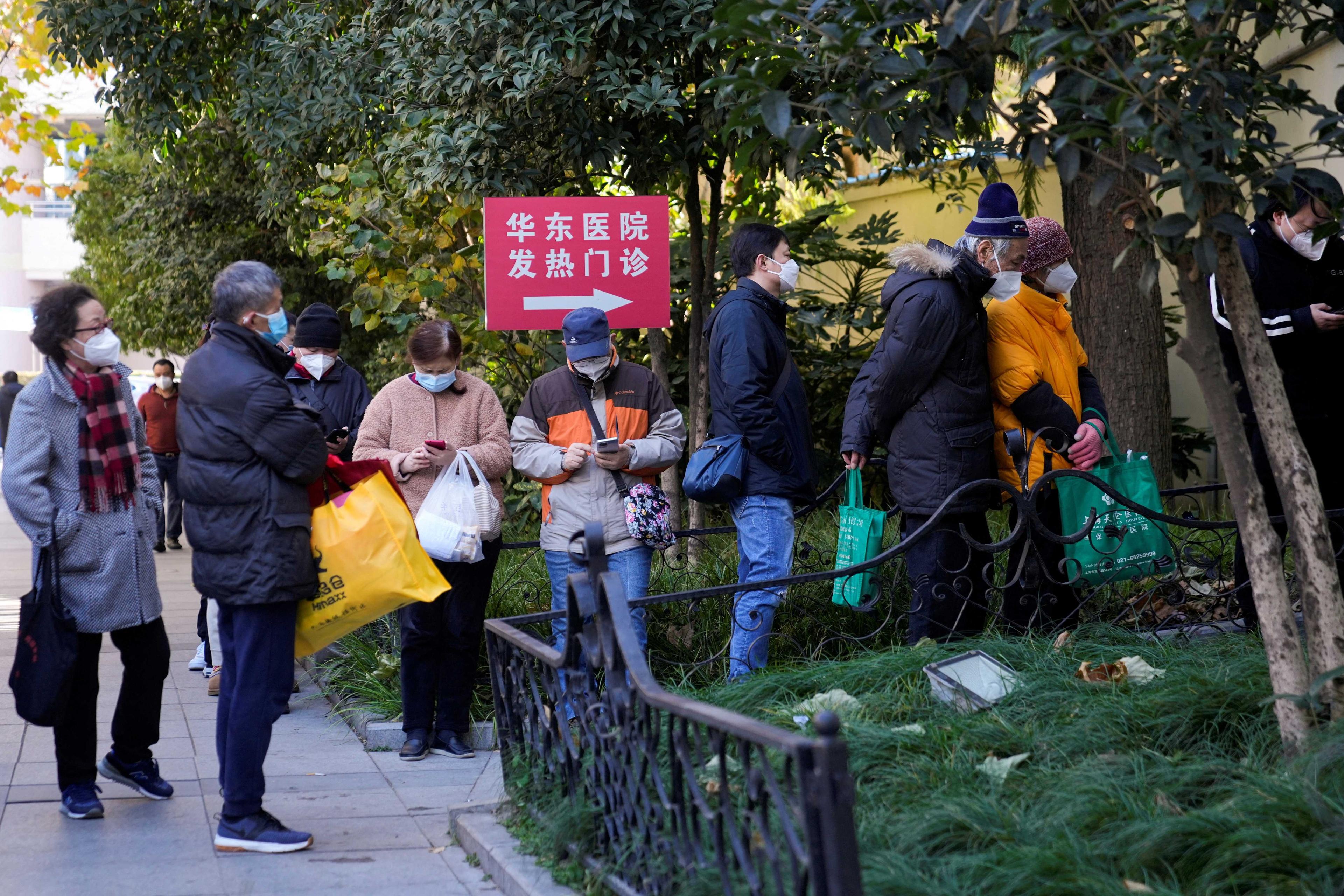 People wearing protective masks line up outside a fever clinic of a hospital, as Covid-19 outbreaks continue in Shanghai, China, Dec 20. Photo: Reuters