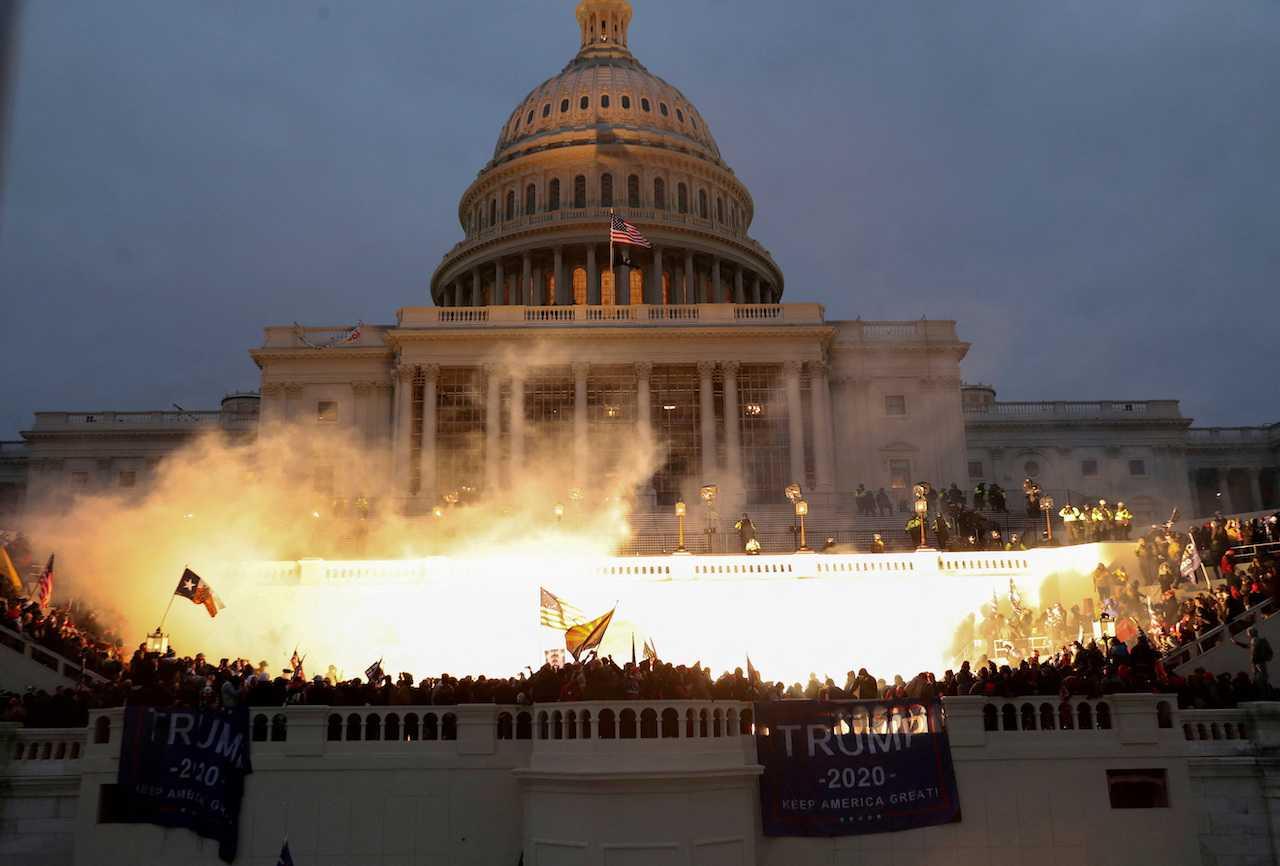 An explosion caused by police munition is seen while supporters of former US president Donald Trump gather in front of the Capitol building in Washington, Jan 6, 2021. Photo: Reuters