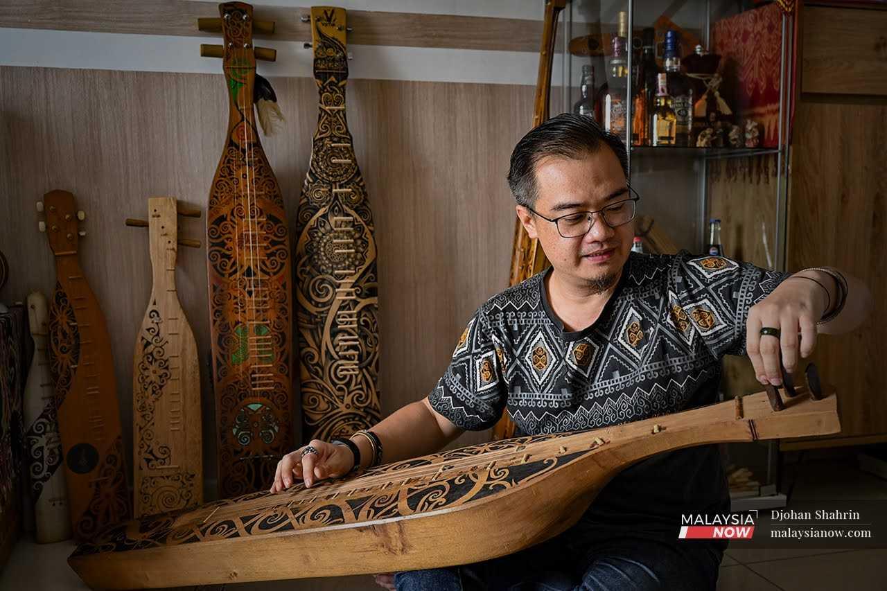 Anderson Kalang tunes a sape, one of several of the traditional Sarawakian instruments he owns, at his home in Kuala Lumpur.