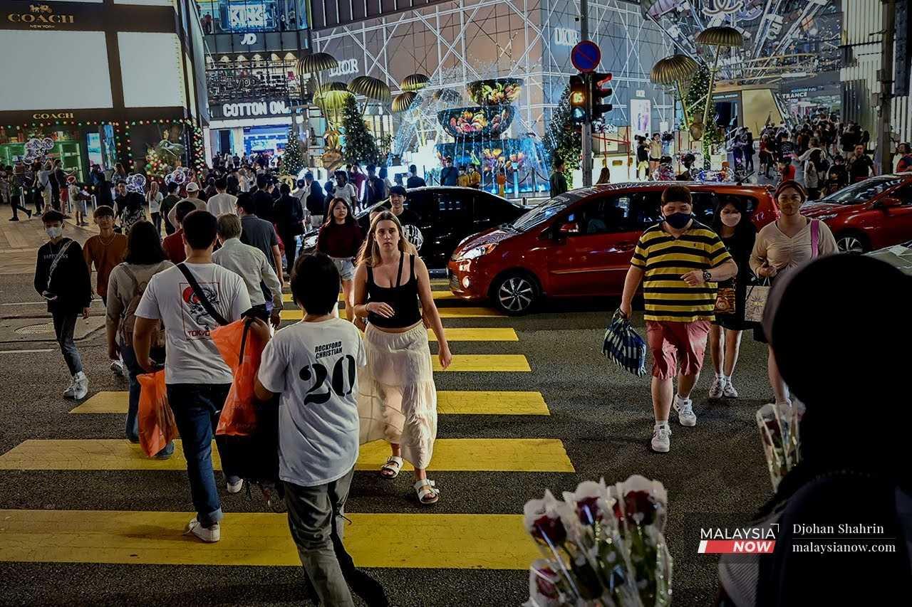 Pedestrians cross a road in the Bukit Bintang shopping district in Kuala Lumpur.
