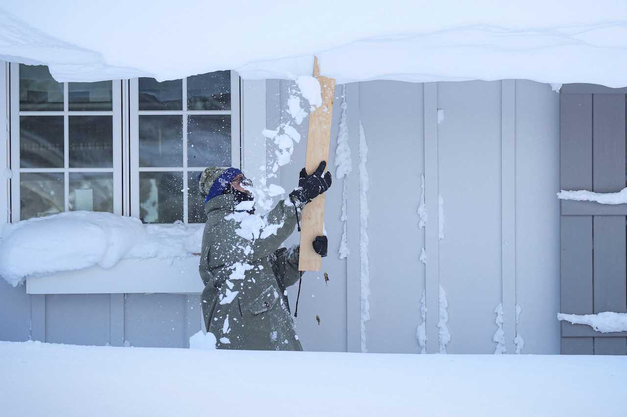 Seorang lelaki membersihkan salji dari bumbungnya berikutan ribut musim sejuk yang melanda wilayah Buffalo di Amherst, New York, 25 Disember. Gambar: Reuters