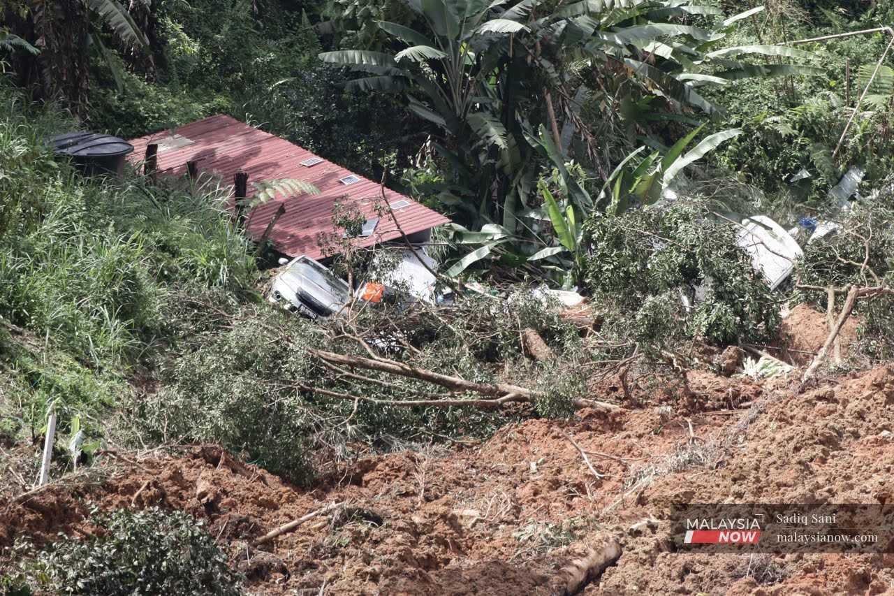 Damaged vehicles lie amid the soil at the site of a landslide that occurred near Father's Organic Farm in Batang Kali.