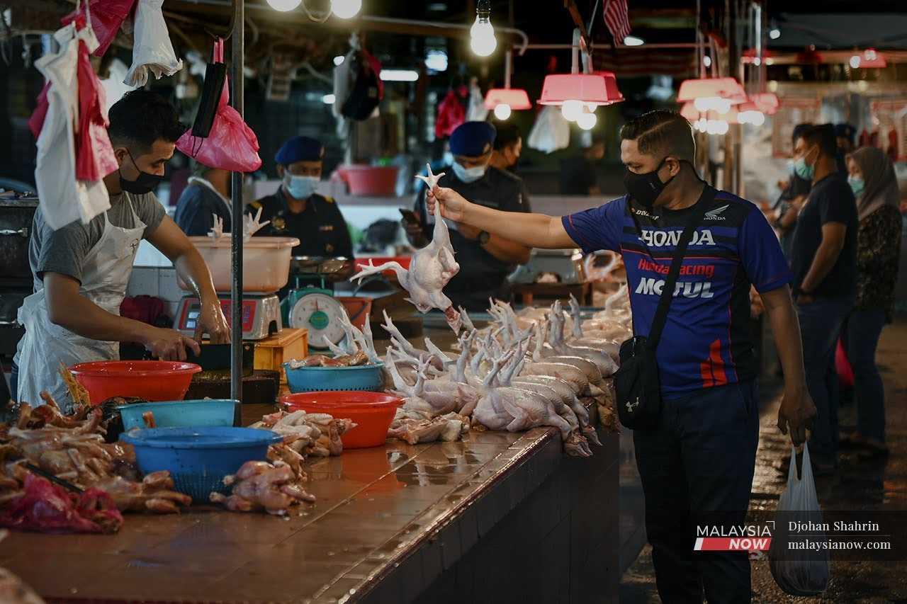 Seorang pelanggan memberikan ayam segar pilihannya kepada penjual untuk dipotong di Pasar Datuk Keramat, Kuala Lumpur.
