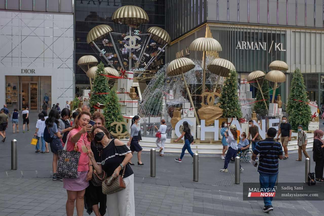 Pelancong mengambil gambil di hadapan hiasan Krismas di kawasan pusat beli-belah di Bukit Bintang, Kuala Lumpur.