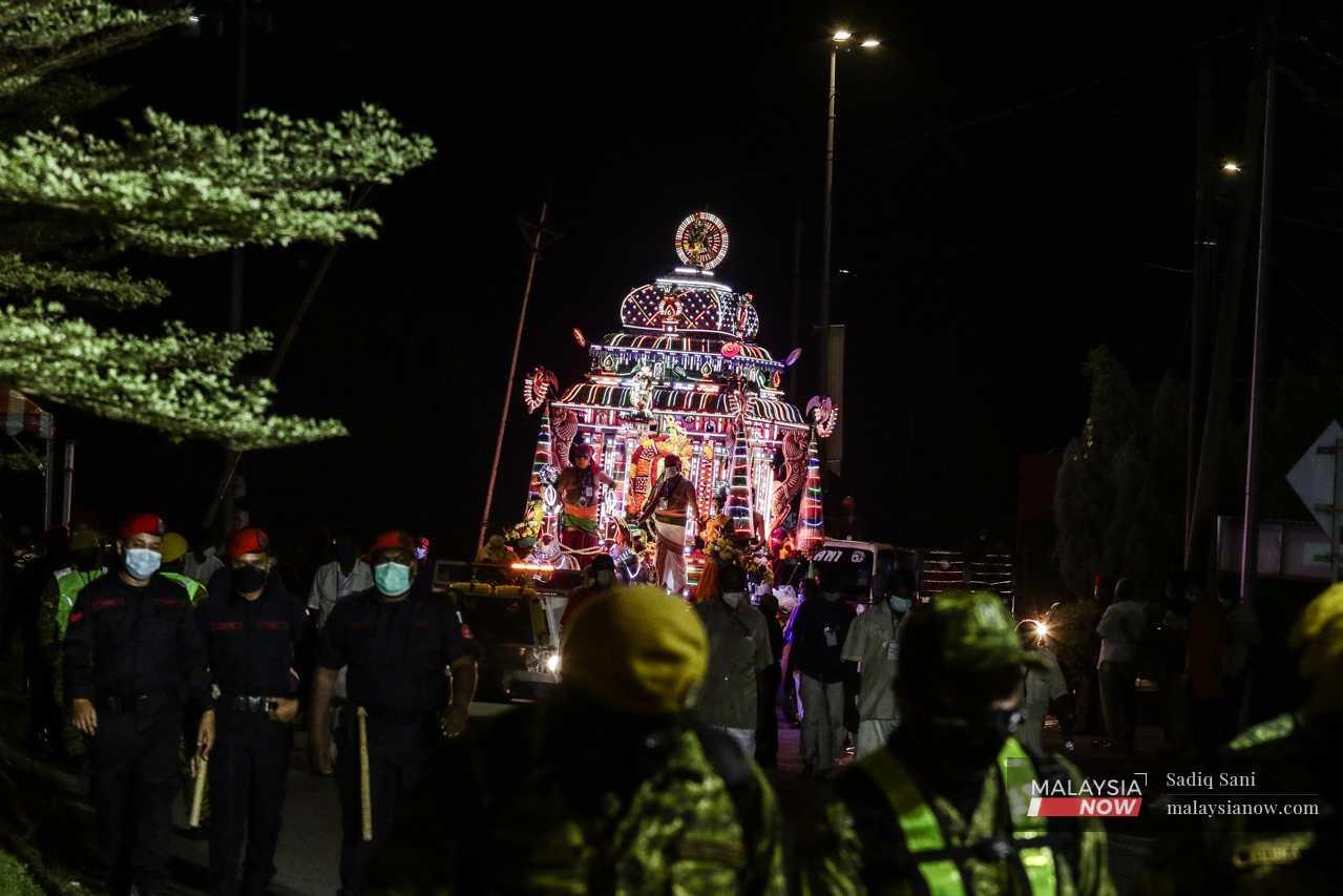 Security personnel escort the chariot of Lord Murugan to prevent crowds from gathering during a Thaipusam procession held under Covid-19 restrictions in Ipoh on Jan 18.