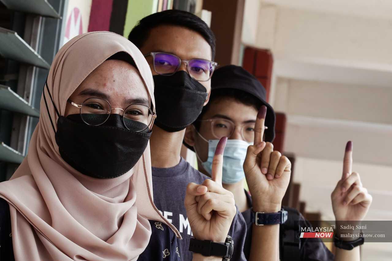 Young voters show their ink-stained fingers after casting their votes for the first time at the Johor election on March 12. 