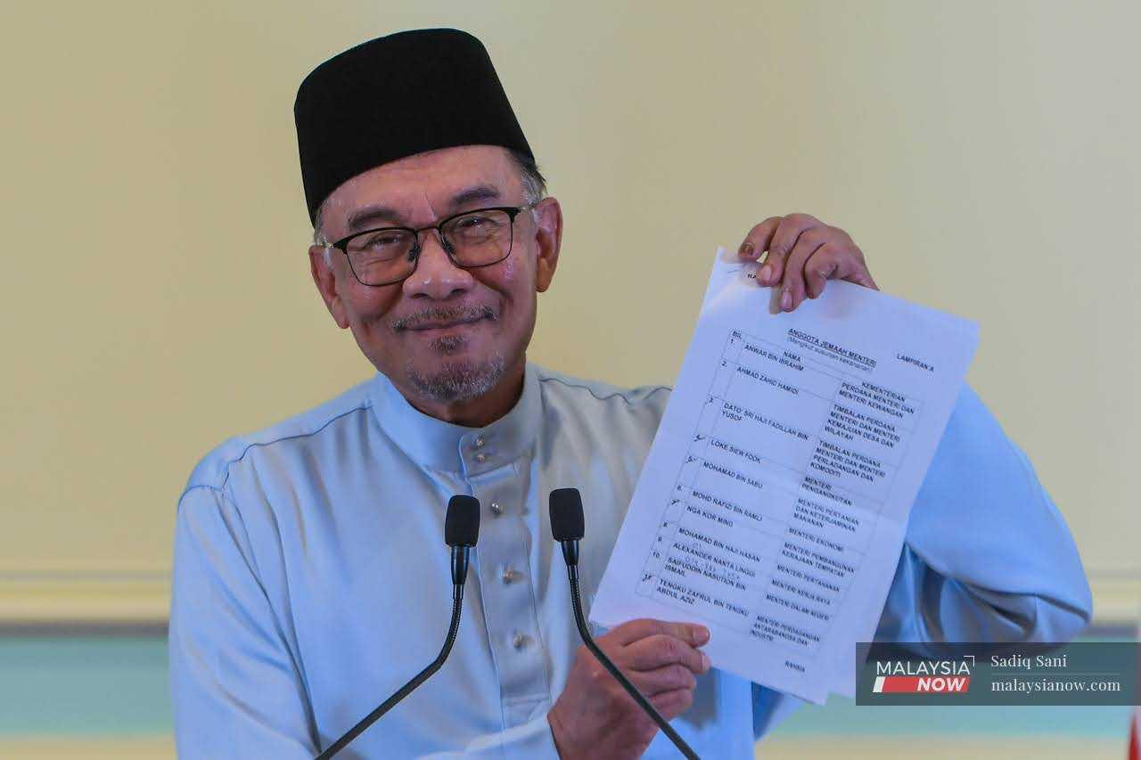 Anwar Ibrahim holds up a list showing his Cabinet line-up, including the controversial appointment of Ahmad Zahid Hamidi as one of his two deputy prime ministers, in Putrajaya on Dec 2. 