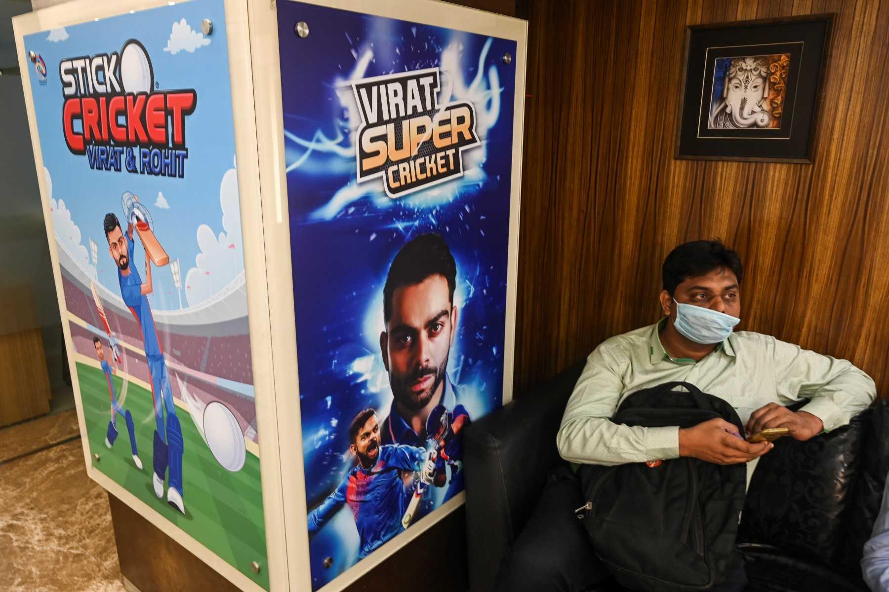A visitor sits next to a poster featuring Indian cricketers Virat Kohli and Rohit Sharma (left) at the reception area of Nazara Technologies Ltd, the country's top mobile cricket gaming app maker, in Mumbai on March 19, 2021. Photo: AFP 