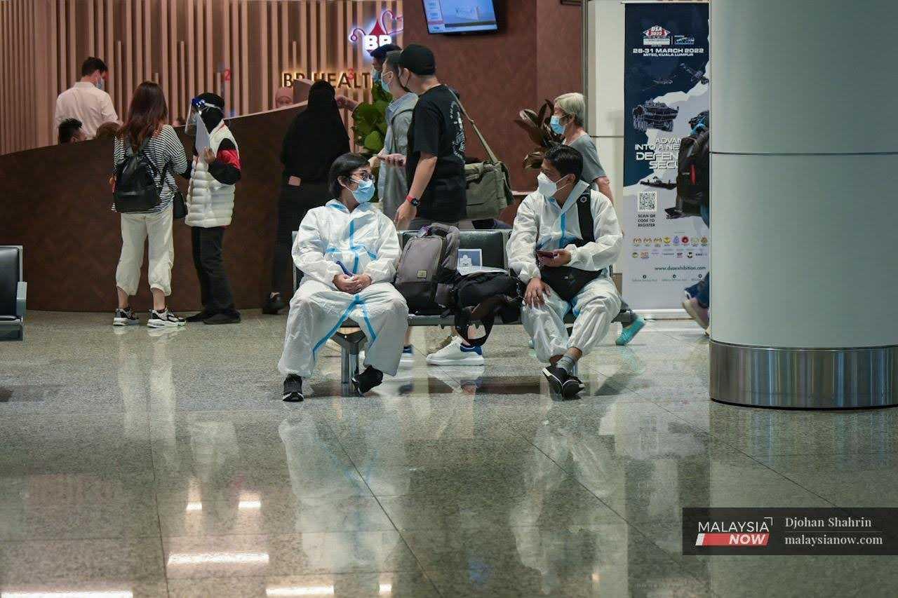 Gambar fail pelancong China memakai baju pelindung ketika duduk di kawasan menunggu KLIA, Sepang.