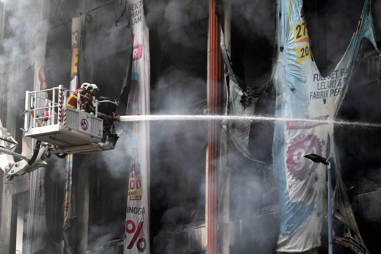 Anggota Jabatan Bomba dan Penyelamat Selangor memadamkan api kebakaran di Wisma Jakel, Seksyen 7, Shah Alam pada 1 Januari. Gambar: Bernama