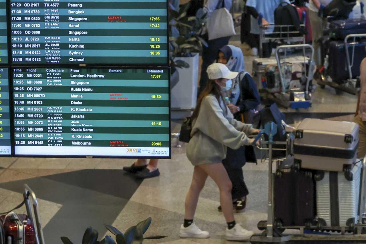 Seorang wanita menolak bagasinya menggunakan troli di KLIA, Sepang. Gambar: Bernama
