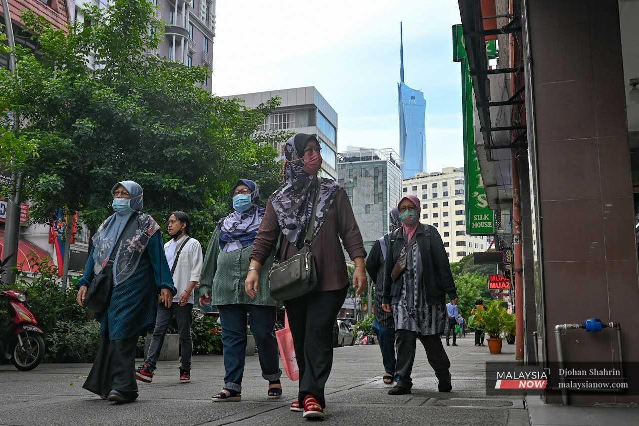 Orang ramai berjalan kaki di pusat bandar Kuala Lumpur dengan memakai pelitup muka bagi membendung Covid-19.