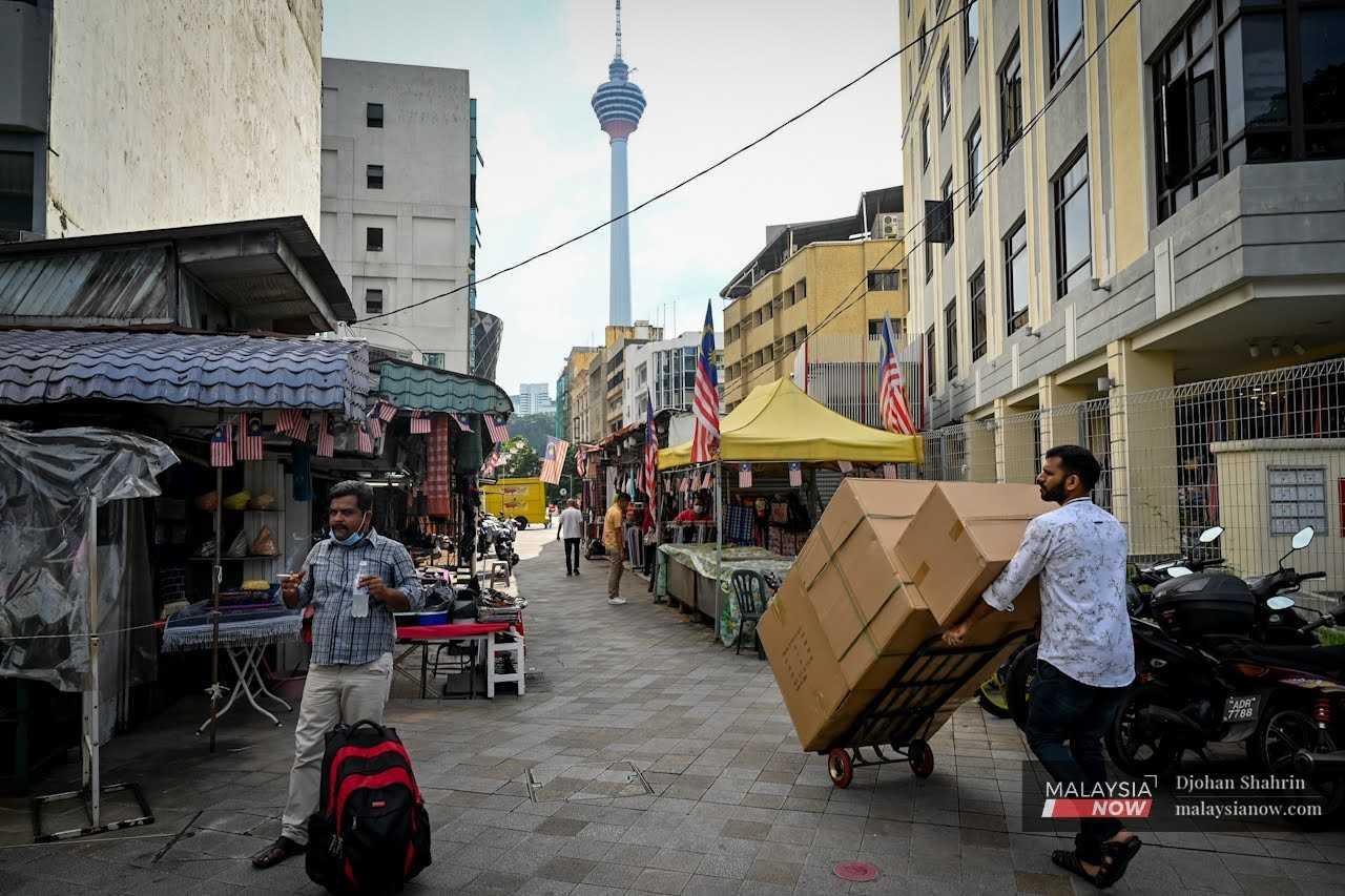 A man pushes stacks of boxes on a trolley at Lorong Bonus 1 in Kuala Lumpur.