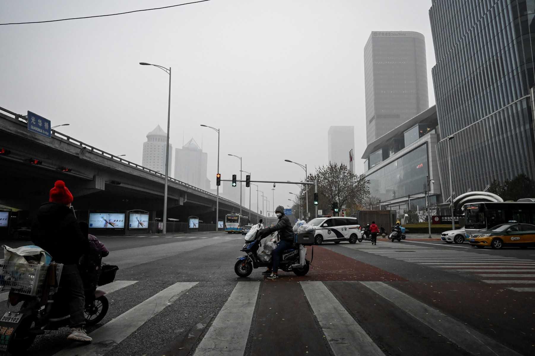 A food delivery man waits for traffic lights at a central business district in Beijing on Nov 24, 2022. Photo: AFP