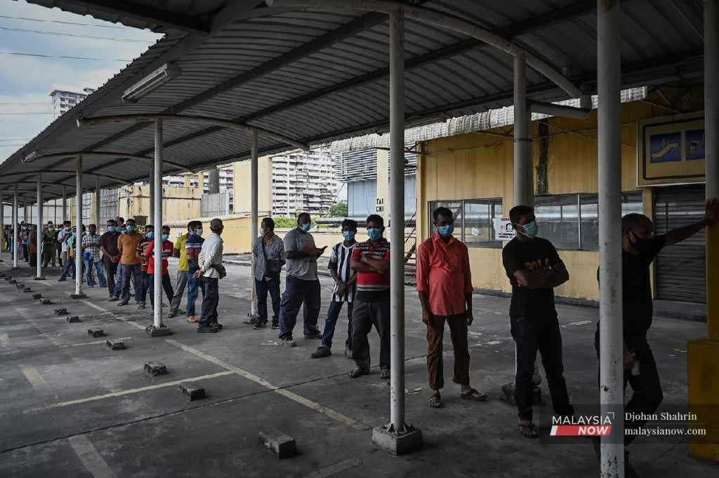 Migrant workers queue in this file picture.