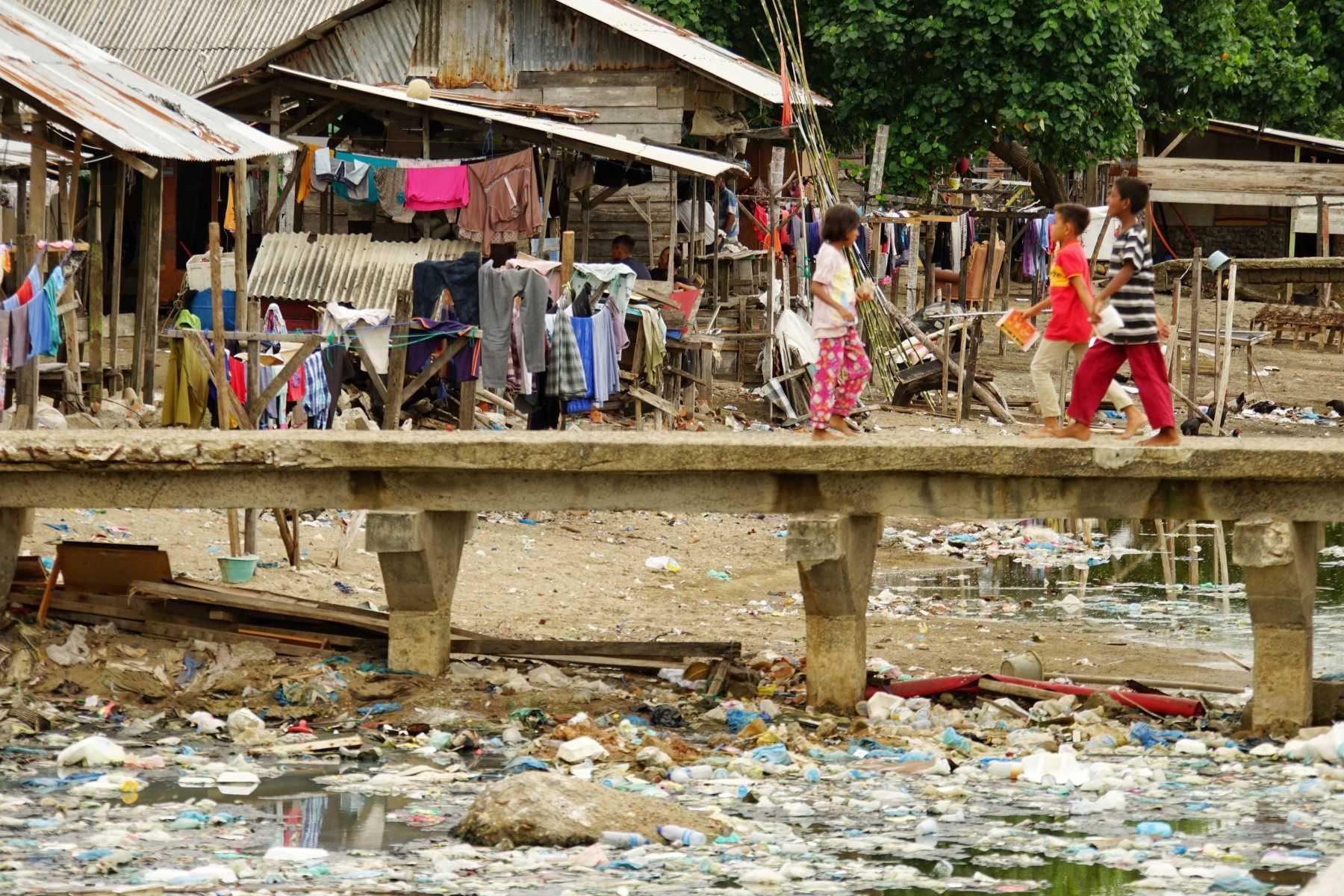 Residents cross a bridge at a river mouth in Lhokseumawe, Aceh on Aug 22, 2021. Photo: Reuters
