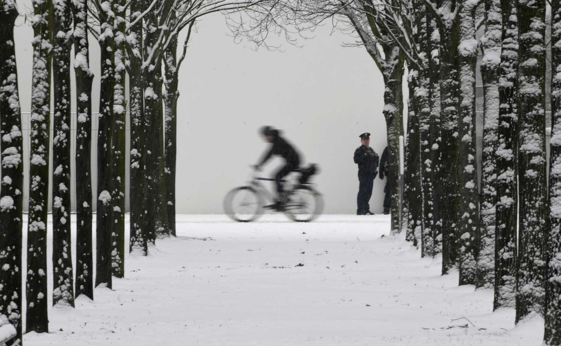 A police officer looks on as a cyclist passes through a snow-covered park near the chancellery in Berlin on Dec 9, 2021. Photo: AFP 