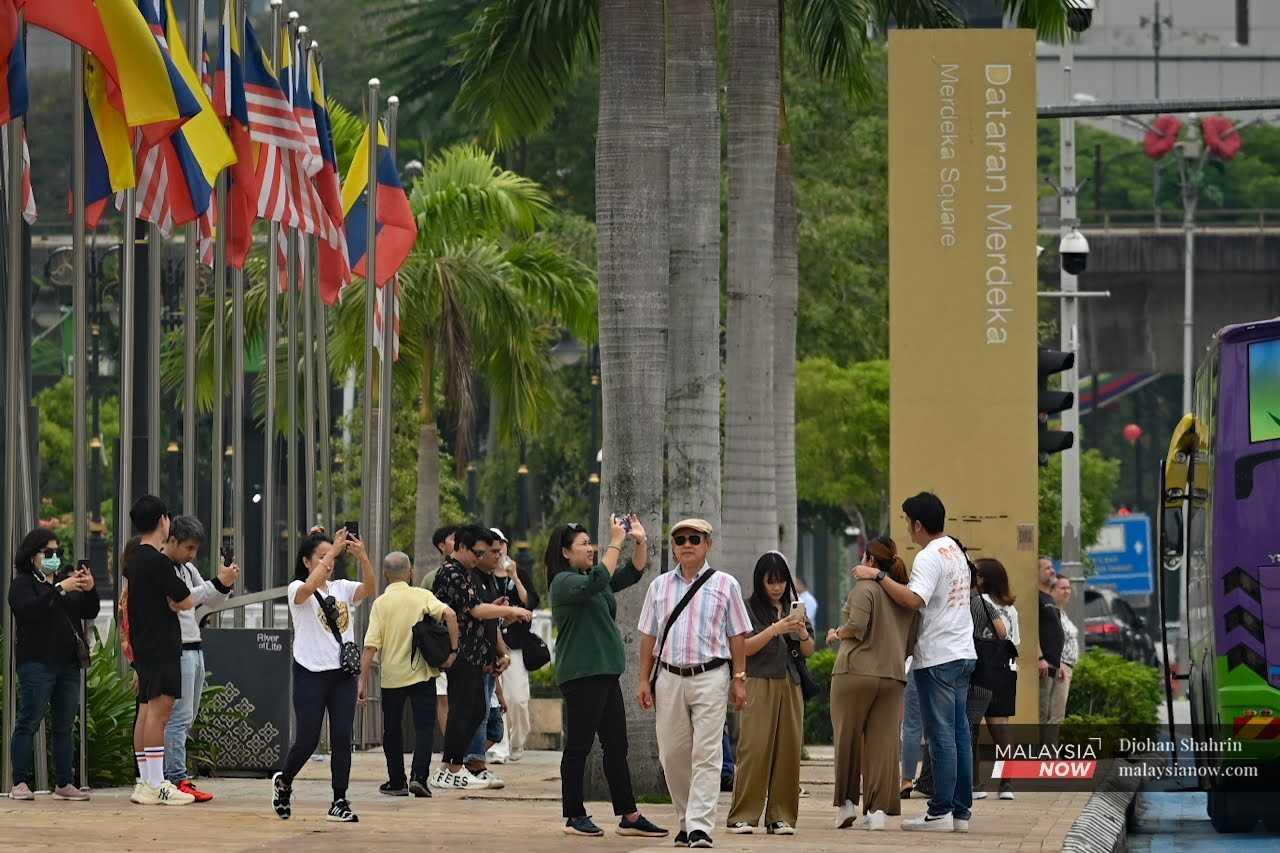 Pelancong mengambil gambar pamandangan sekeliling ketika bersiar-siar di sekitar Dataran Merdeka, Kuala Lumpur.