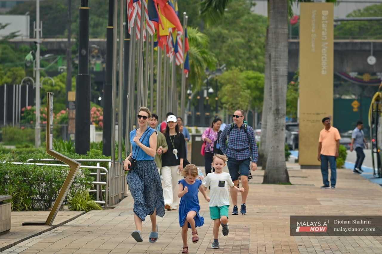 A woman smiles as she runs after her children at Dataran Merdeka in Kuala Lumpur.