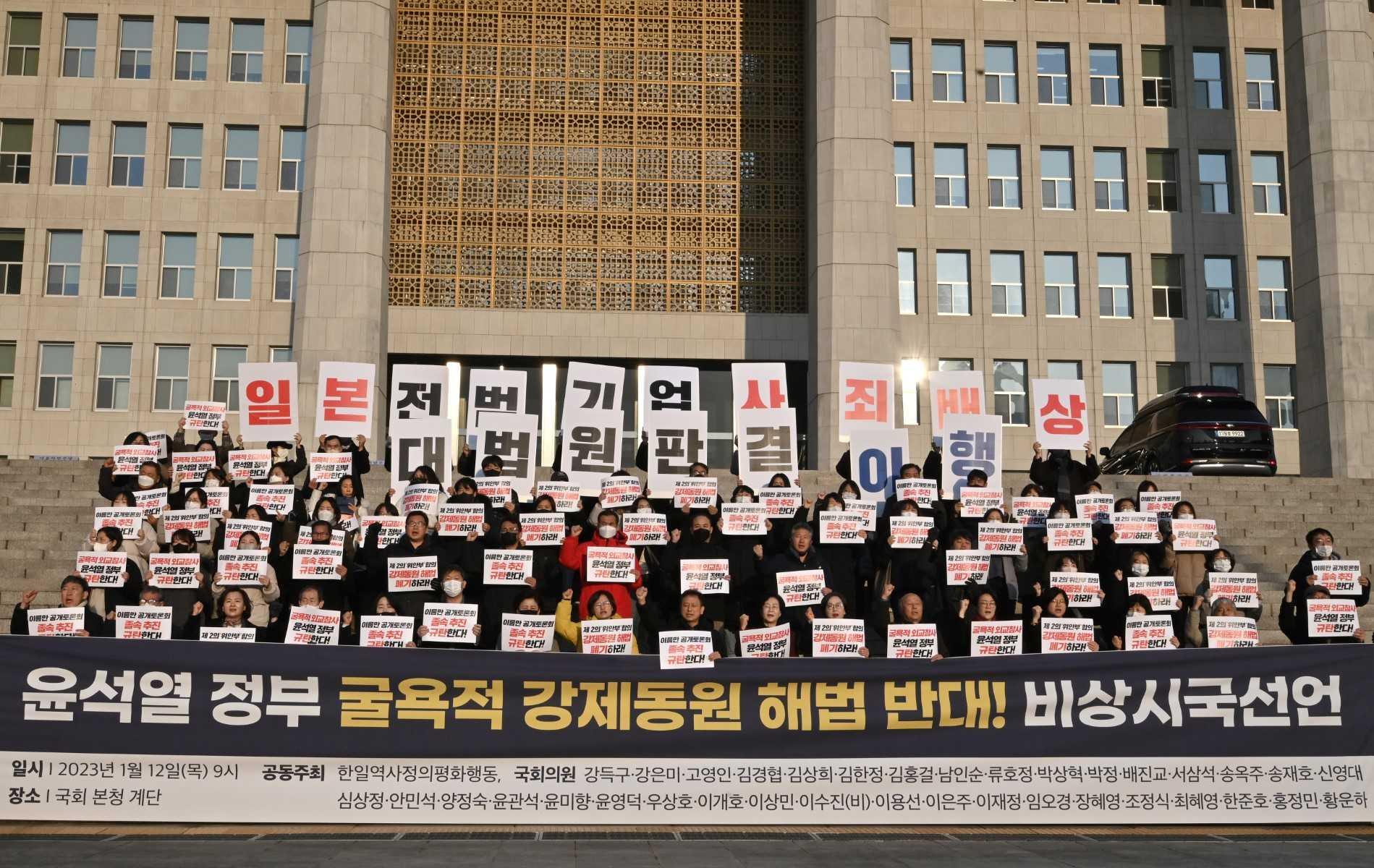 South Korean opposition lawmakers and supporters of the victims of Japan's wartime forced labour hold placards reading 'We oppose the Yoon Seok-yeol government's humiliating solution to the forced labour issue!' during a protest against a public hearing on the issue at the National Assembly in Seoul on Jan 12. Photo: AFP