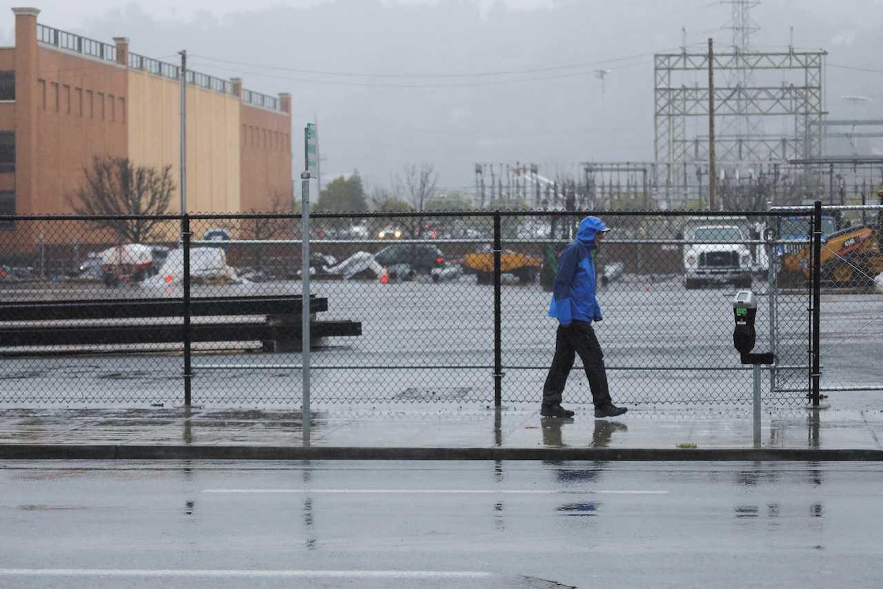A man walks in the rain during a recent string of storm systems in San Rafael, California, Jan 11. Photo: Reuters