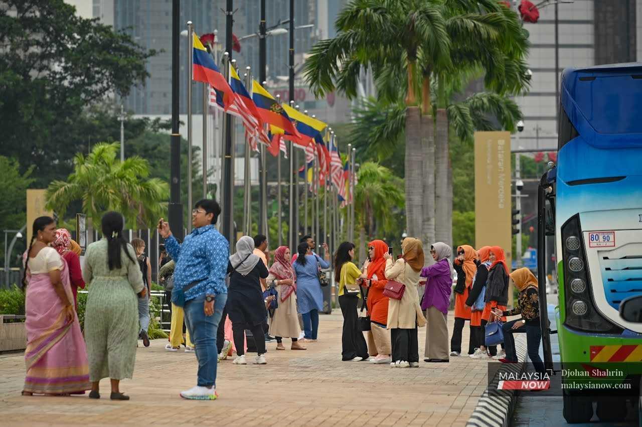 Pelancong dari India dan Indonesia bersiar-siar sambil bergambar di Dataran Merdeka.