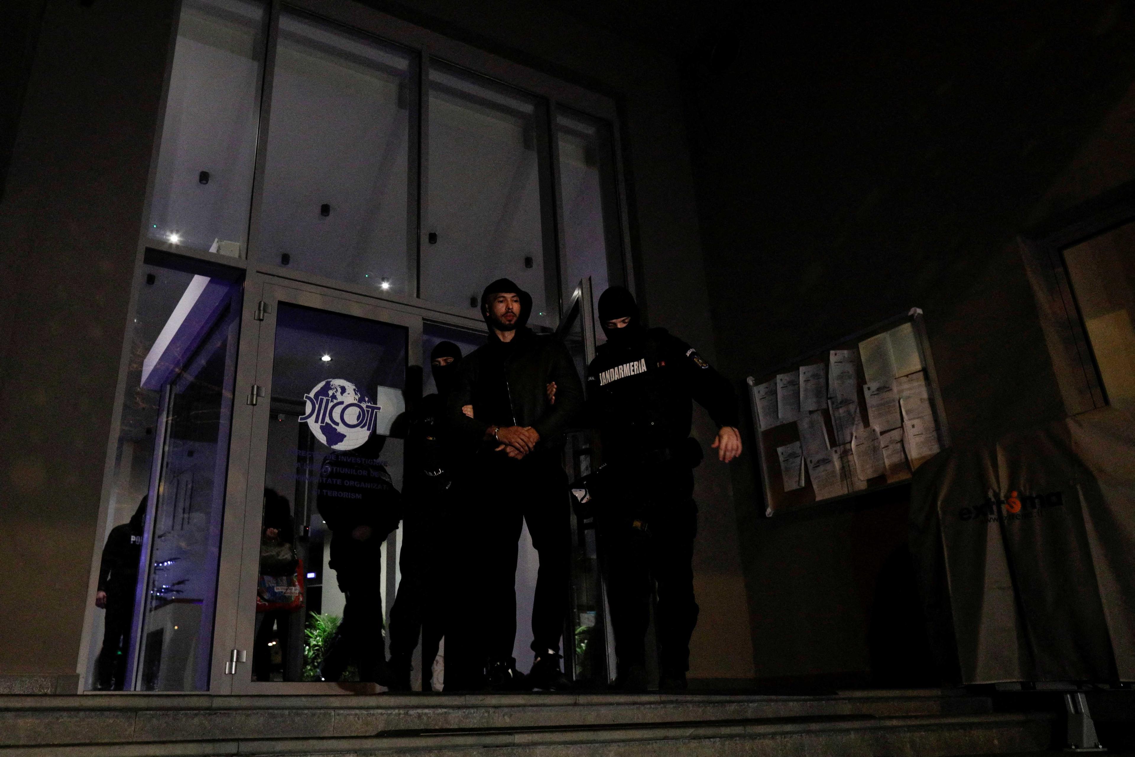 Andrew Tate and Tristan Tate (not pictured) are escorted by police officers outside the headquarters of the Directorate for Investigating Organized Crime and Terrorism in Bucharest after being detained for 24 hours, in Bucharest, Romania, Dec 29, 2022. Photo: Reuters