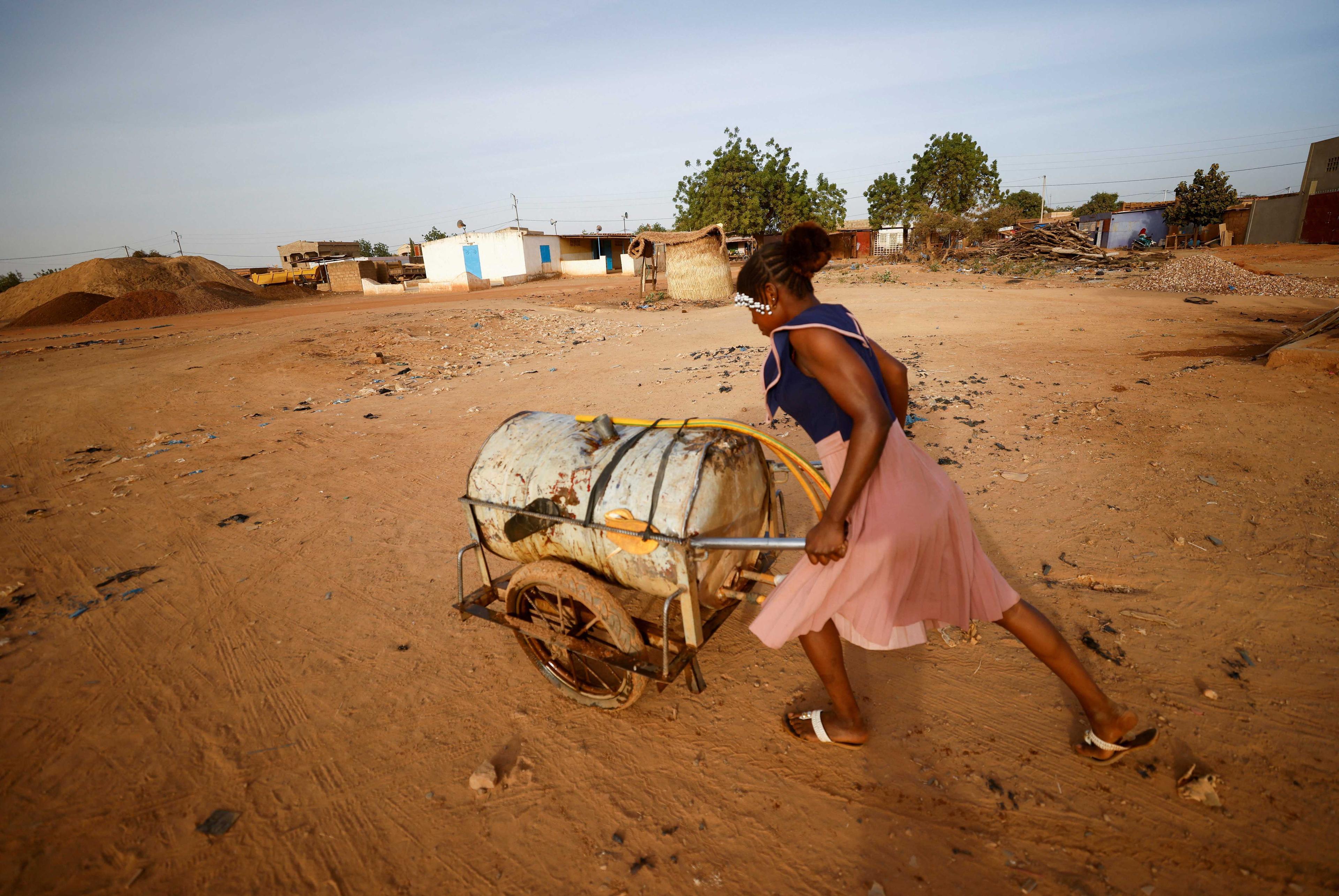 A woman pushes a barrel filled with water on the outskirts of Ouagadougou, Burkina Faso Jan 30, 2022. Photo: Reuters
