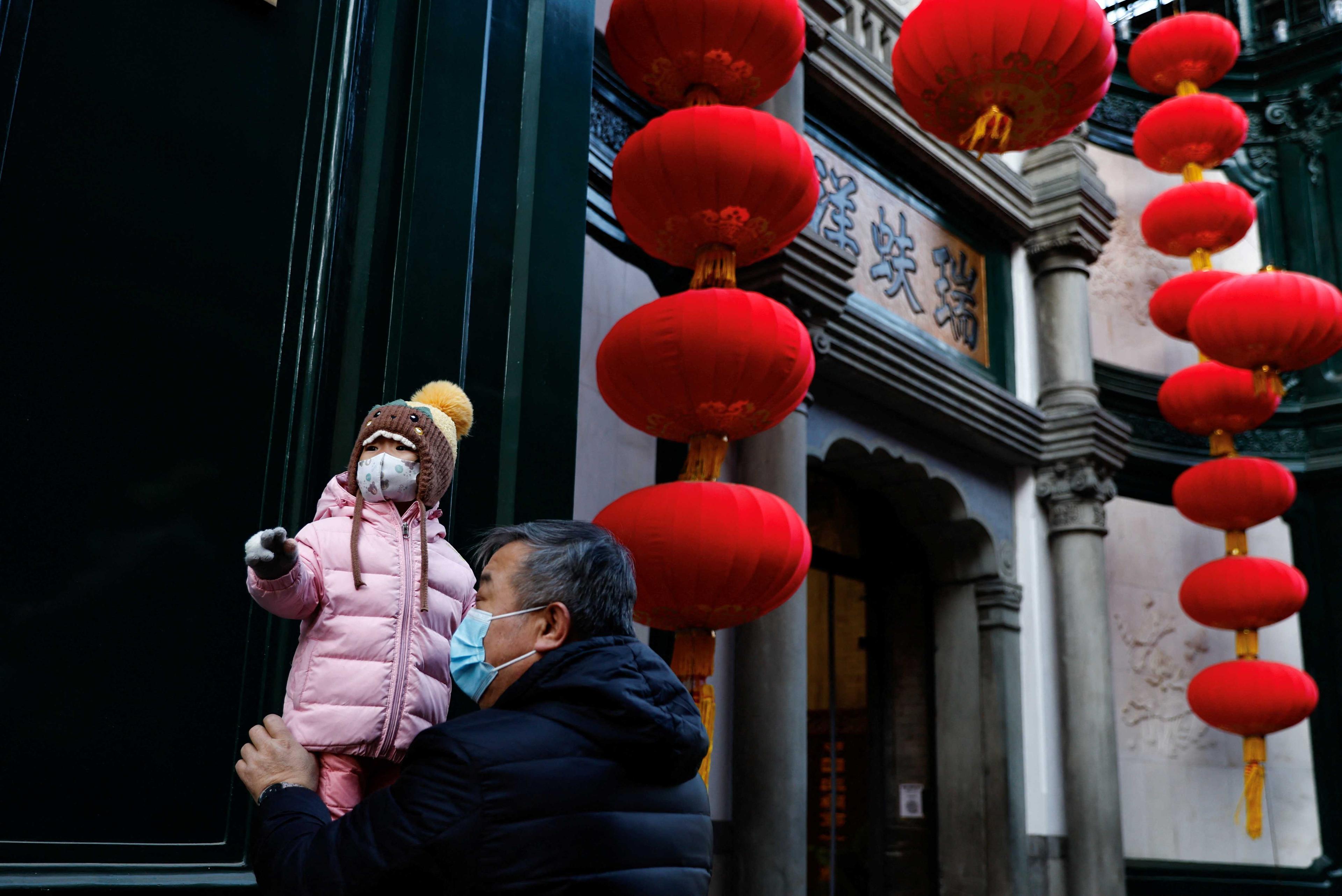 An elderly person holds a child near lanterns decorating a shop ahead of the Chinese Lunar New Year, in Beijing, China, Jan 15. Photo: Reuters