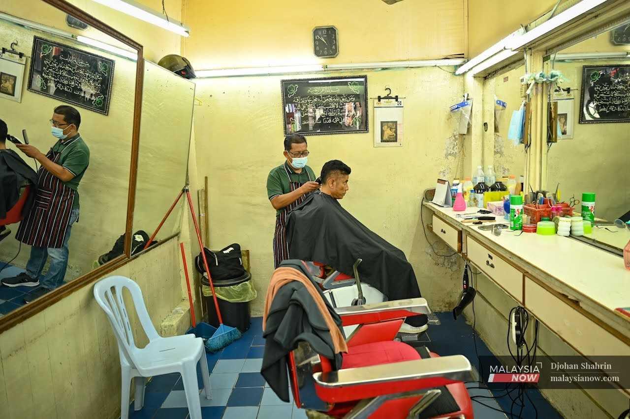 Peniaga Ahmad Mat, 55, yang menyediakan perkhidmatan gunting rambut di ibu kota tetap mengamalkan prosedur operasi standard dengan memakai pelitup muka meskipun negara sudah beralih ke fasa pemulihan.