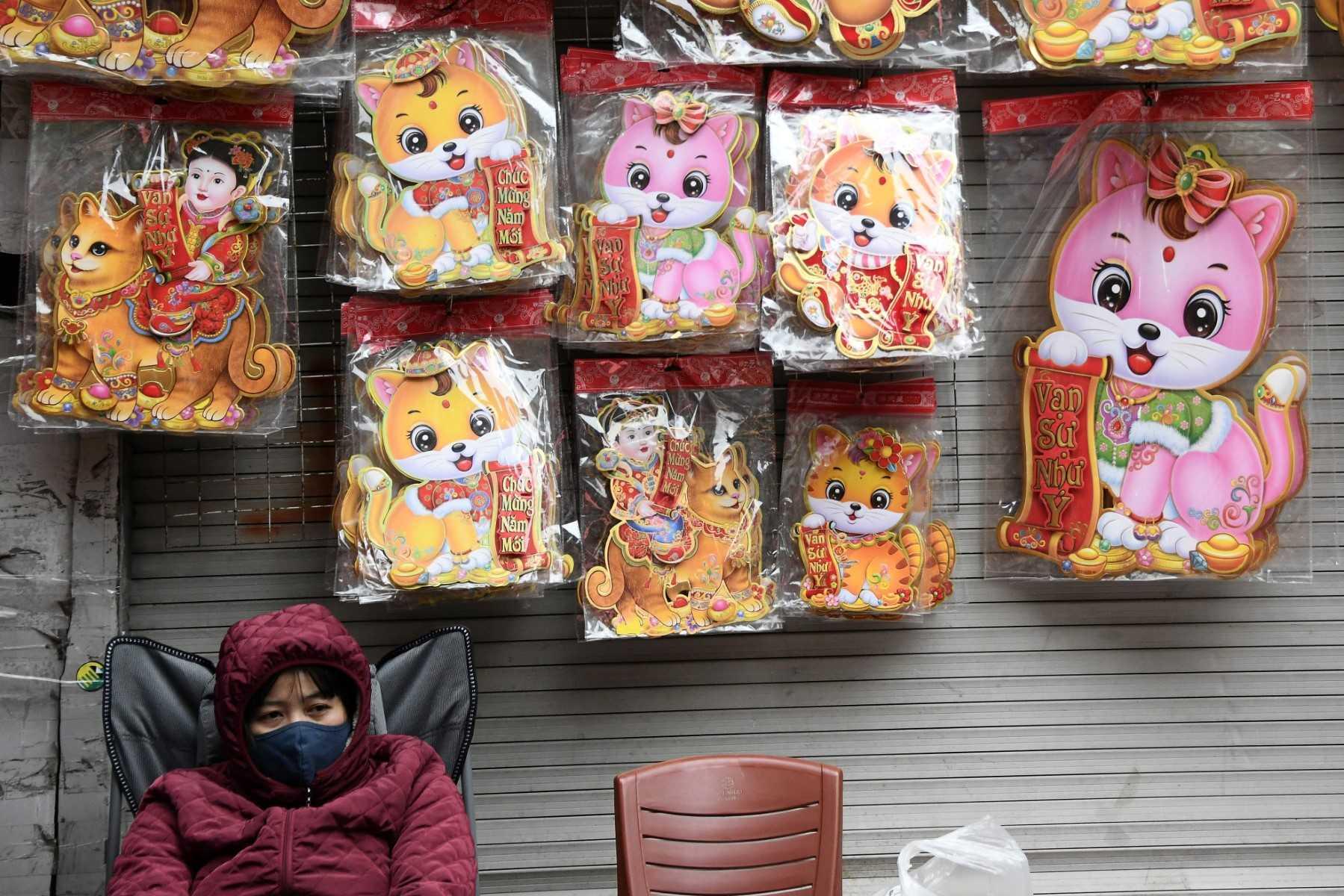 A shopkeeper waits for customers at a stall selling cat decorations at a market in the old quarters of Hanoi, Jan 17. Photo: AFP