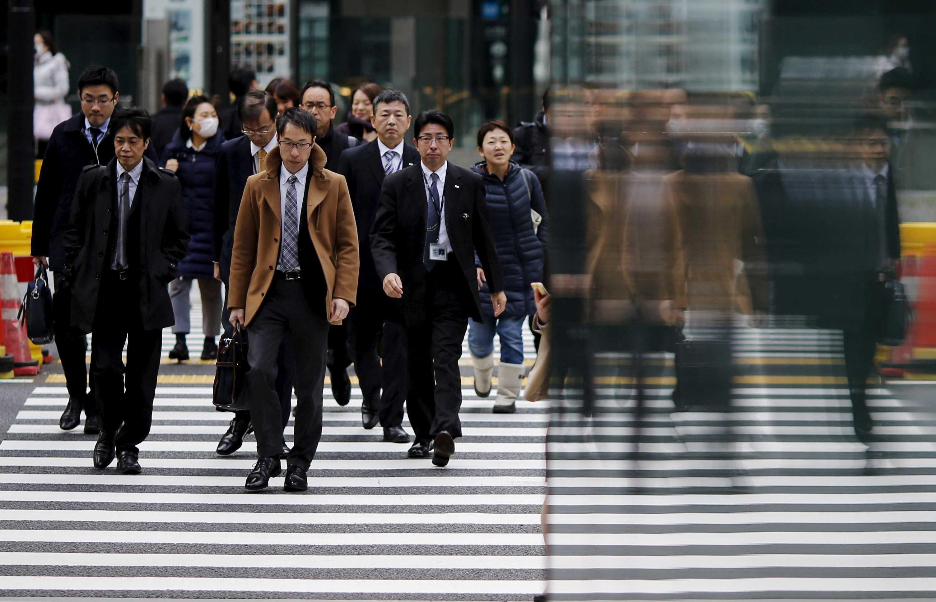People are reflected on a wall as they cross a road at Tokyo's business district, Japan, Feb 22, 2016. Photo: Reuters