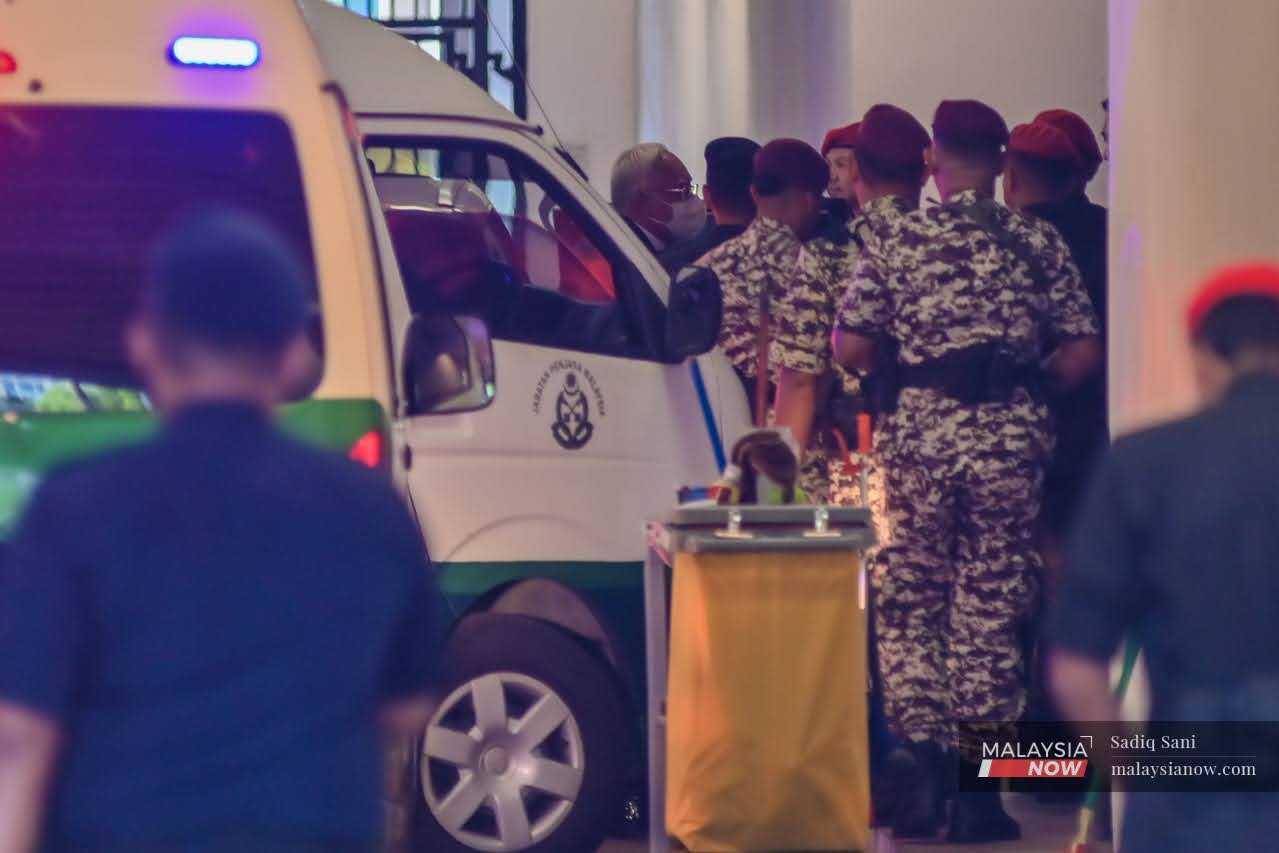 Bekas perdana menteri Najib Razak diiringi pegawai penjara sebaik tiba di Istana Kehakiman di Putrajaya, 19 Januari.