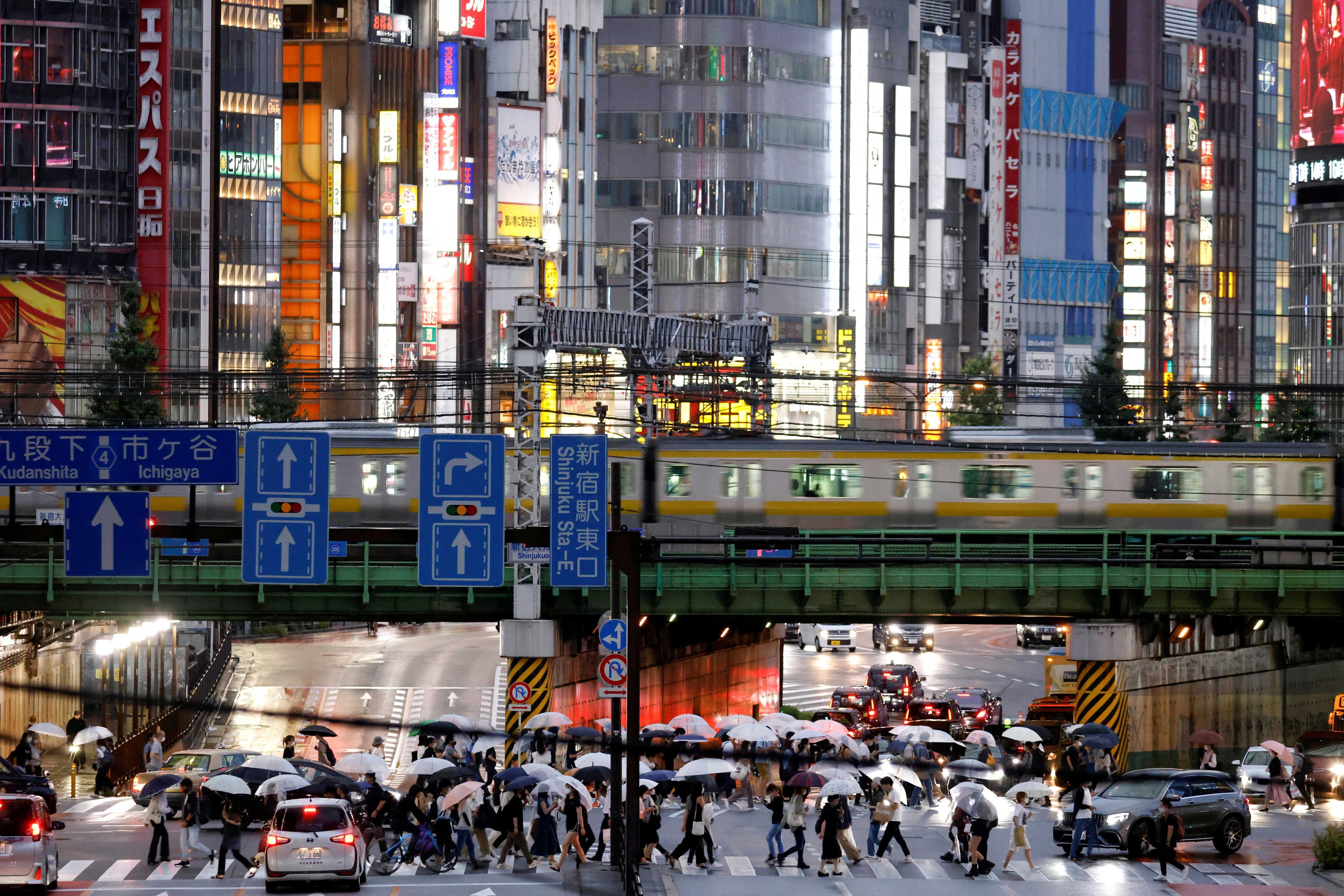 Commuters make their way along an avenue next to Shinjuku station during a rainy day in Tokyo, Japan, Aug. 14, 2021. Photo: Reuters
