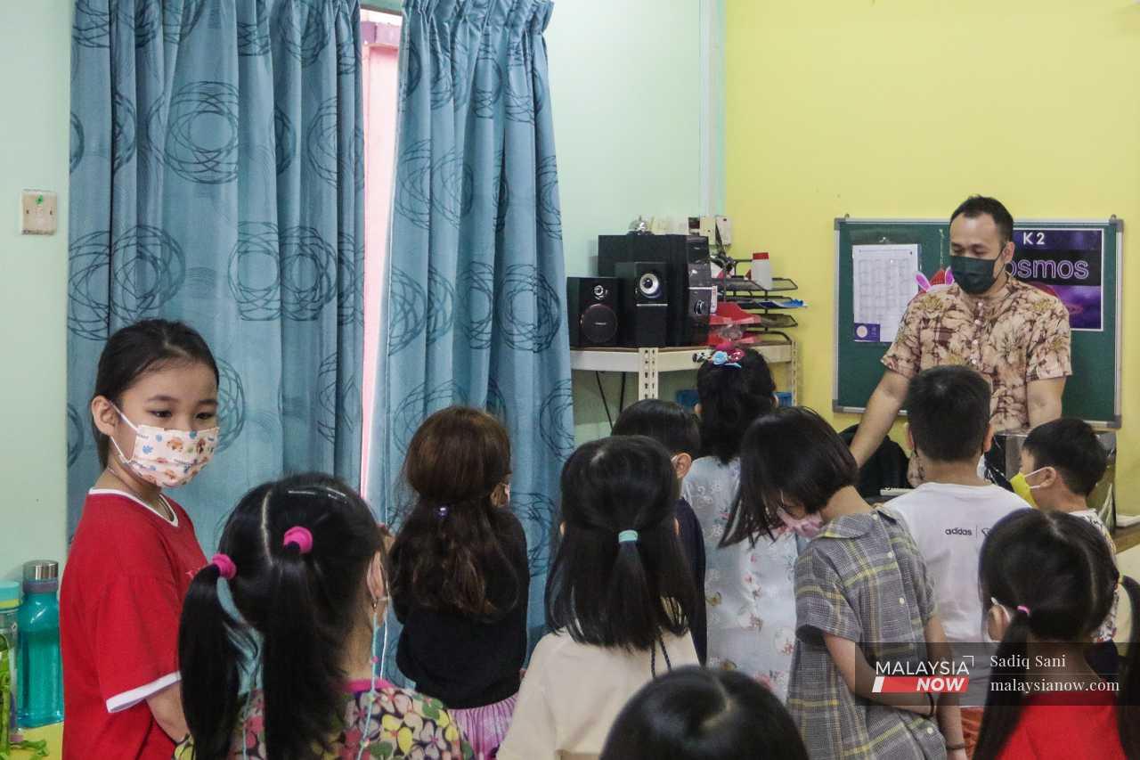 Suki (left) looks over her shoulder at her classmates as their teacher speaks to them about an upcoming concert.