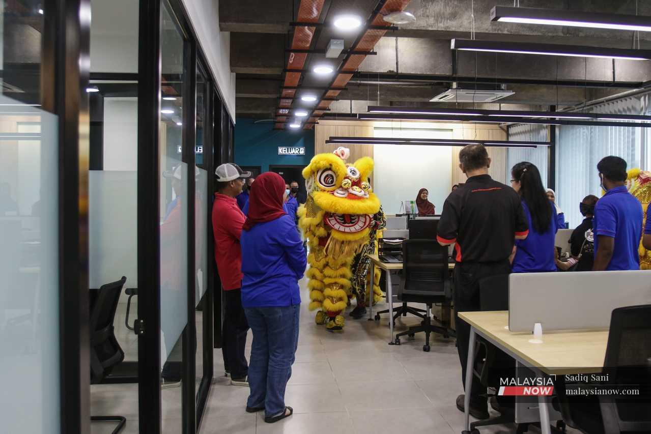 The office workers watch as the lion makes its way through the building. 