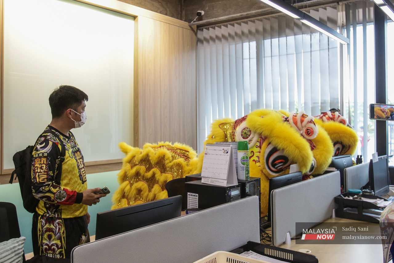 During a performance at an office in Klang, the lion goes around placing oranges on each desk to invite prosperity for the new year. 