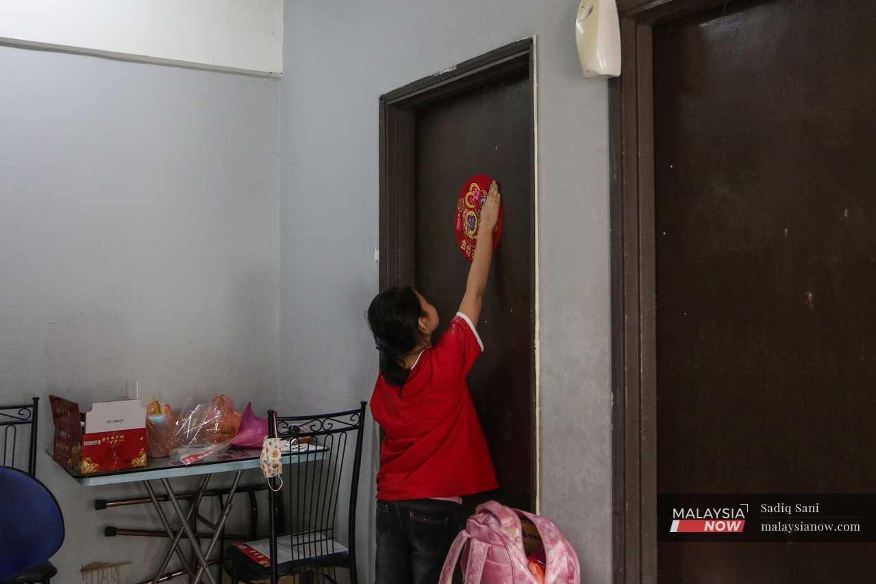 At home, she stands on tiptoe, reaching as high as she can to paste a red sticker on her bedroom door. 