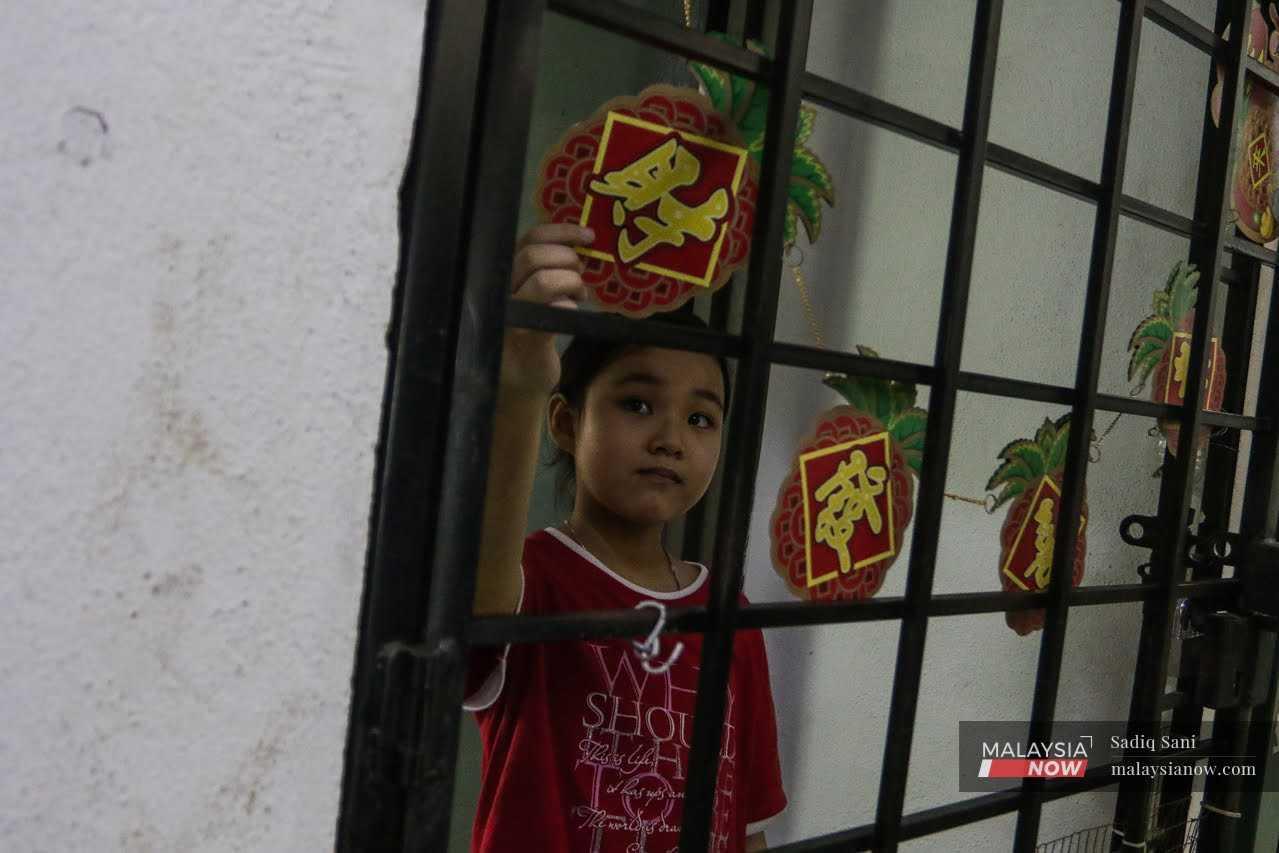 Young Suki Wong touches a string of pineapple decorations hung at the front door of her small flat. 
