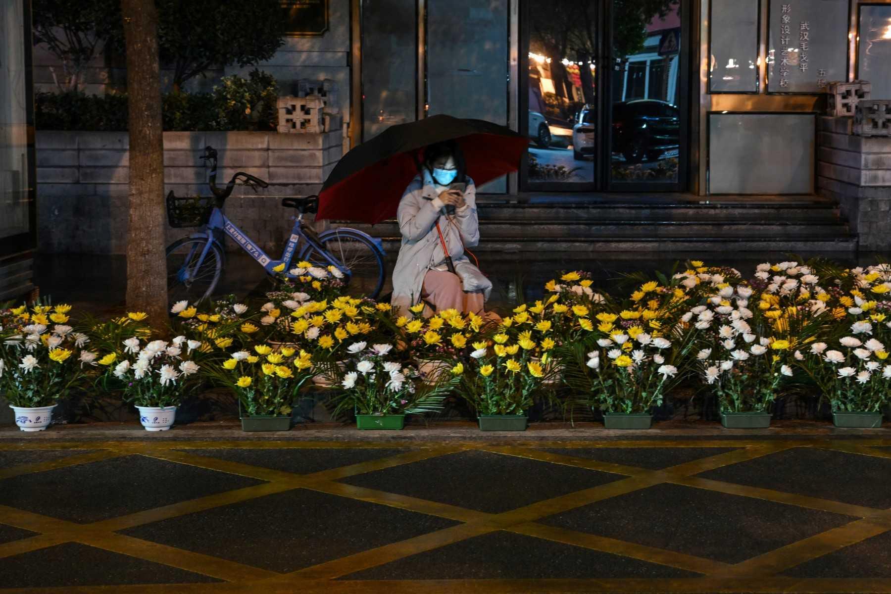 A woman selling flowers along a street waits for customers on the eve of the Lunar New Year in Wuhan, in China's central Hubei province on Jan 21. Photo: AFP