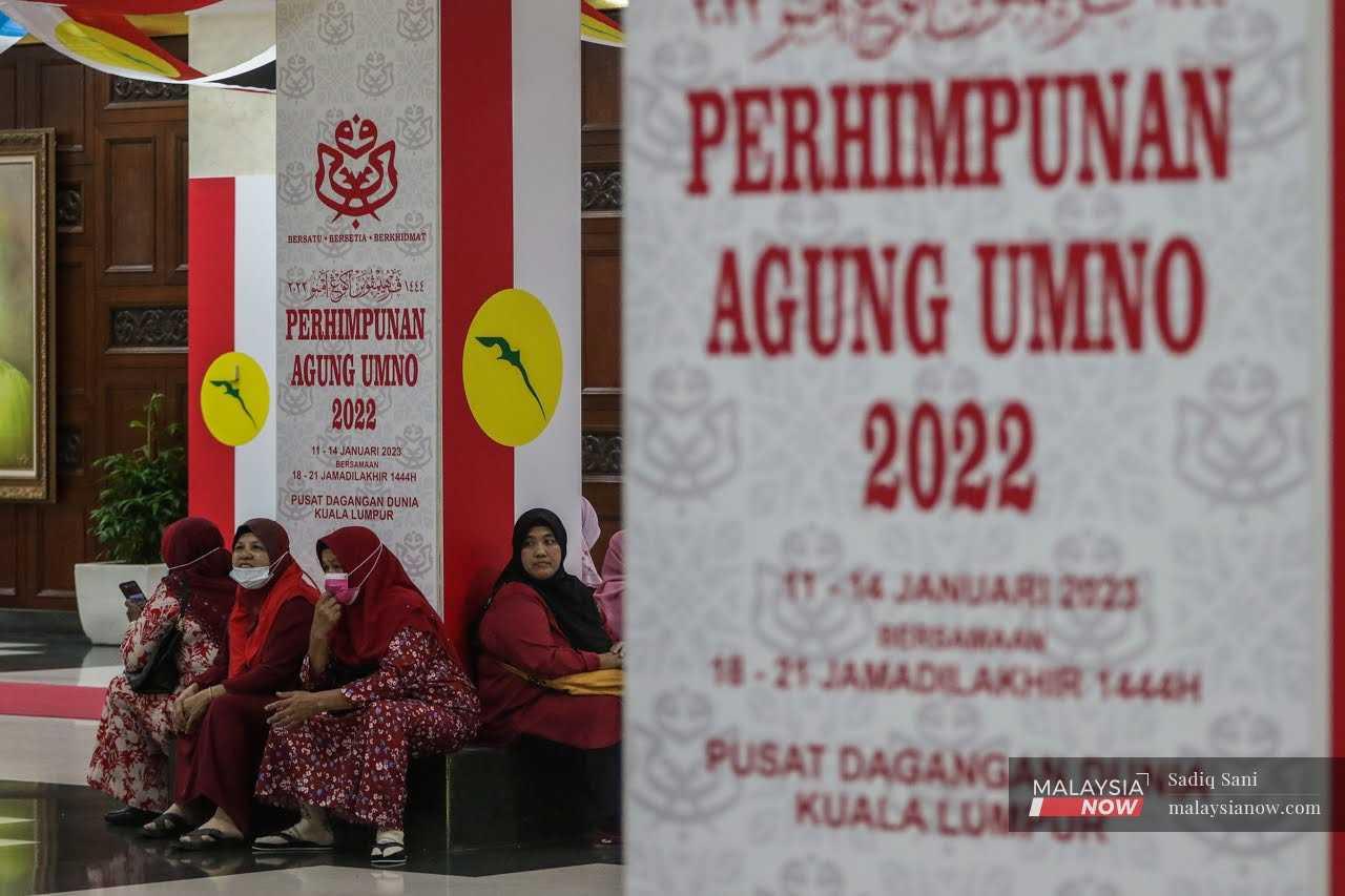 Penyokong parti mengikuti perbahasan Perhimpunan Agung Umno 2022 yang disiarkan pada skrin gergasi di lobi Pusat Dagangan Dunia Kuala Lumpur, 11 Januari.
