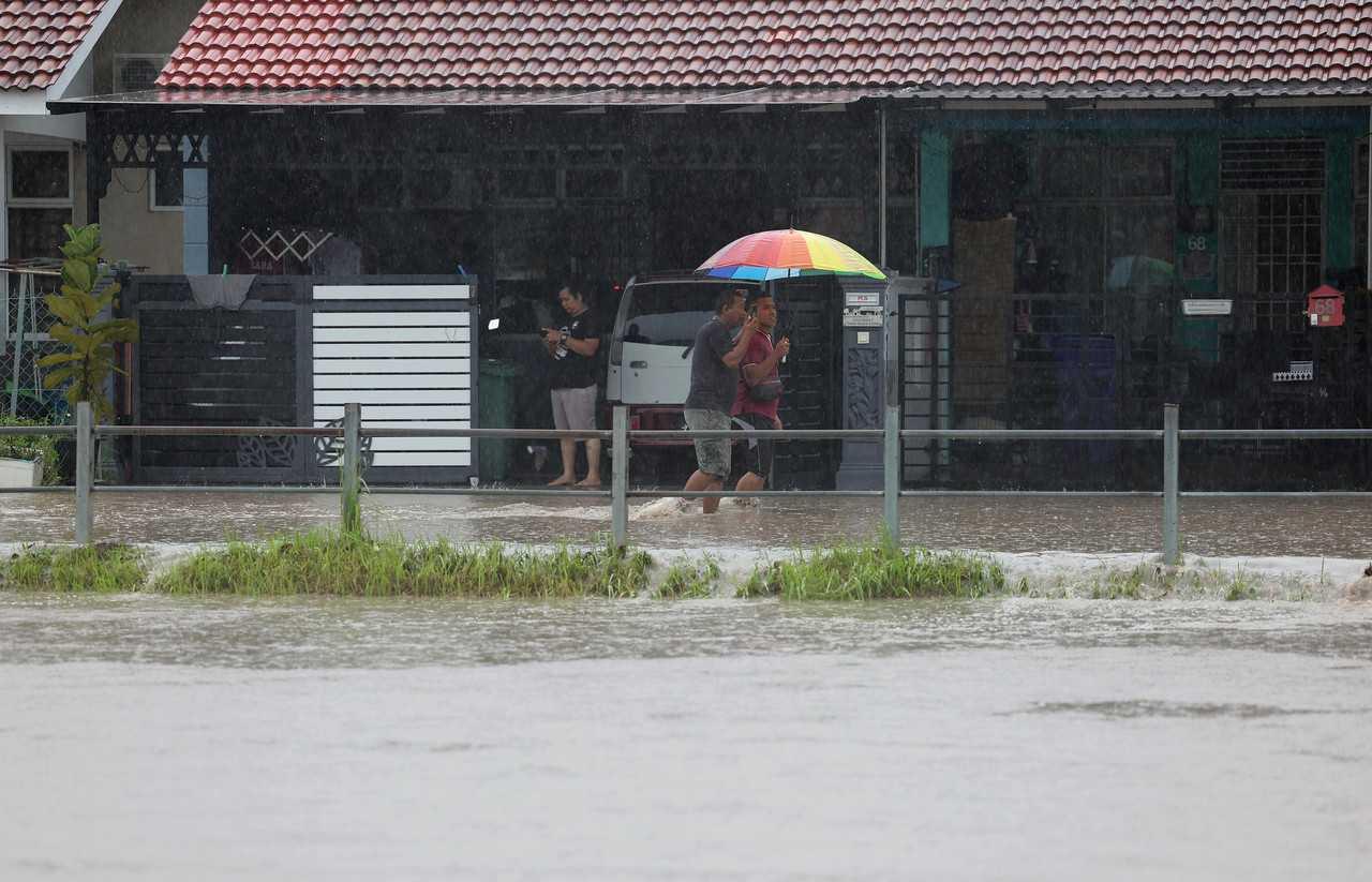 Residents wade through knee-deep water at Taman Desaru Utama in Kota Tinggi, Johor, Jan 24. Photo: Bernama