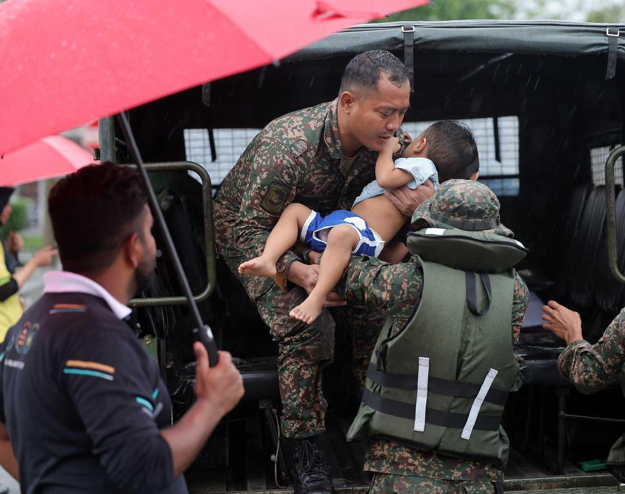 Army personnel evacuate a young boy from his home in Taman Desaru Utama, Bandar Penawar in Kota Tinggi, Johor. Photo: Bernama