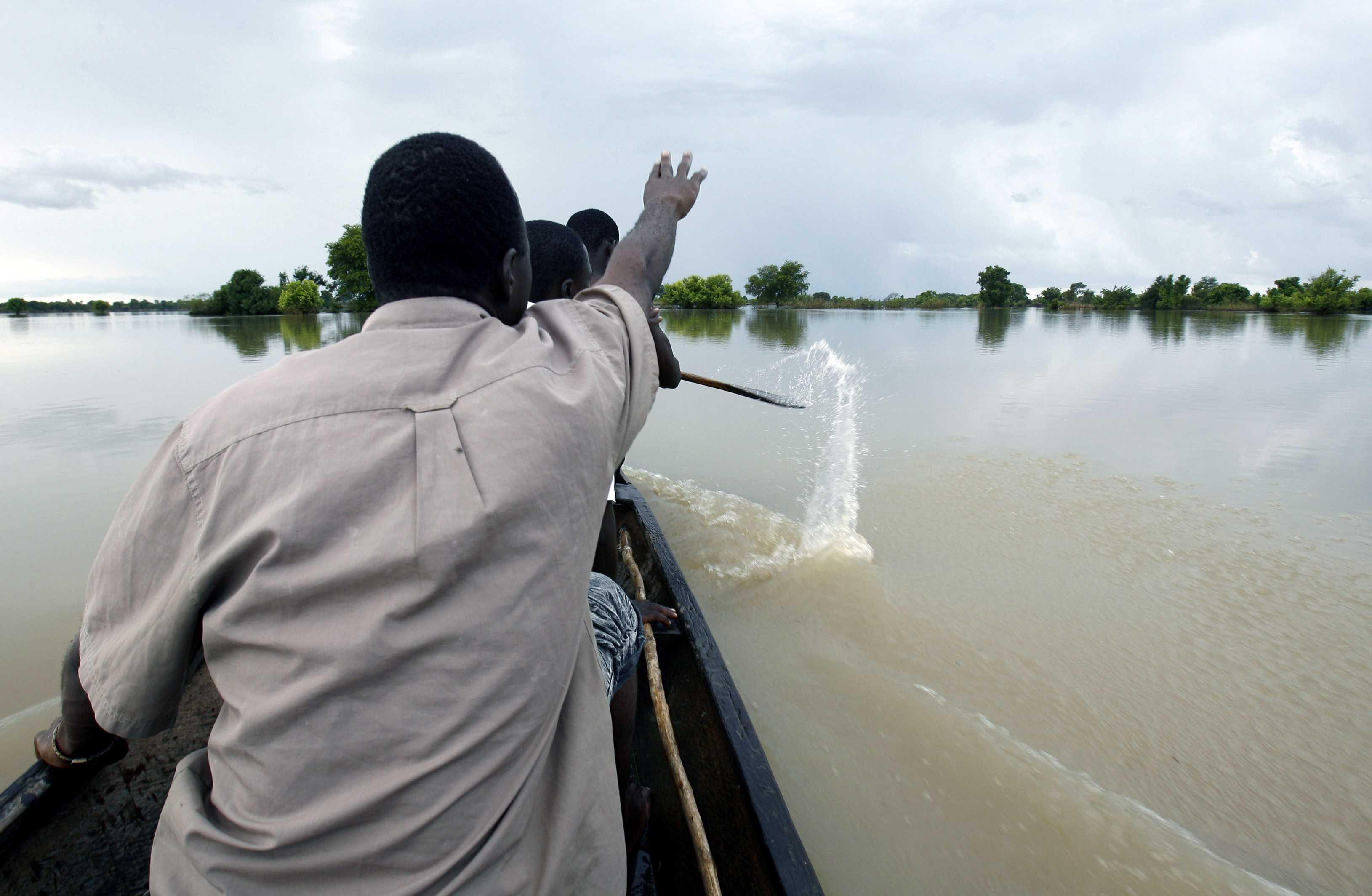 Penduduk mendayung sampan melintasi kawasan bendang yang ditenggelami air selepas Tasik Volta melimpah akibat hujan lebat, 23 September 2007. Gambar: AFP